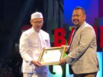 Mewakili keluarga Pondok Pesantren Mambaus Sholihin Suci Manyar Gresk Dr KH Moh Najib, Lc menerima penghargaan GPA PWI Gresik yang diserahkan oleh Bupati Gresik H Fandi Akhmad Yani. Foto: dok PWI Gresik/NUGres