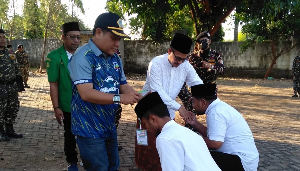 Rais Syuriyah MWCNU Ujungpangkah KH Mahrus Munir bersama Camat Ujungpangkah saat mengalungkan ID Card peserta sebagai pembukaan secara simbolis. Foto: dok PAC GP Ansor Ujungpangkah/NUGres