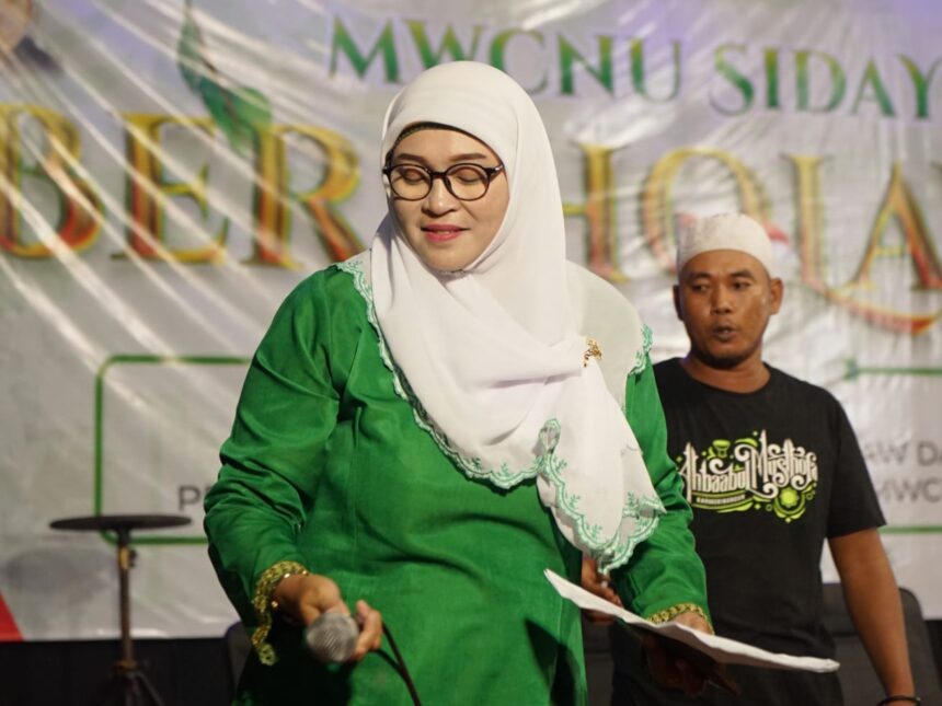 Anggota Muslimat NU Sidayu, Masbaha, saat bertugas sebagai MC di acara "MWCNU Sidayu Bersholawat". Foto: dok MWCNU Sidayu/NUGres