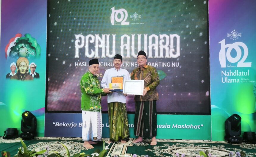 Pj Rais Syuriyah PCNU Gresik KH Moh. Farhan, bersama Wakil Bupati Gresik dr Asluchul Alif, menyerahkan piagam penghargaan kepada Juara Umum MWCNU, dalam PCNU Gresik Award Tahun 2025, Sabtu (22/2/2025). Foto: Jalil/NUGres