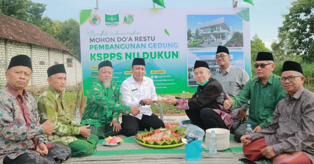 Rais Syuriah MWCNU Dukun Dr KH Thoyyib Mas'udi memberikan tumpeng kepada Ketua KSPPS NU Dukun H. Mu'anan di momen peletakan batu pertama pembangunan kantor baru KSPPS NU Dukun. Foto: dok KSPPS NU Dukun/NUGres